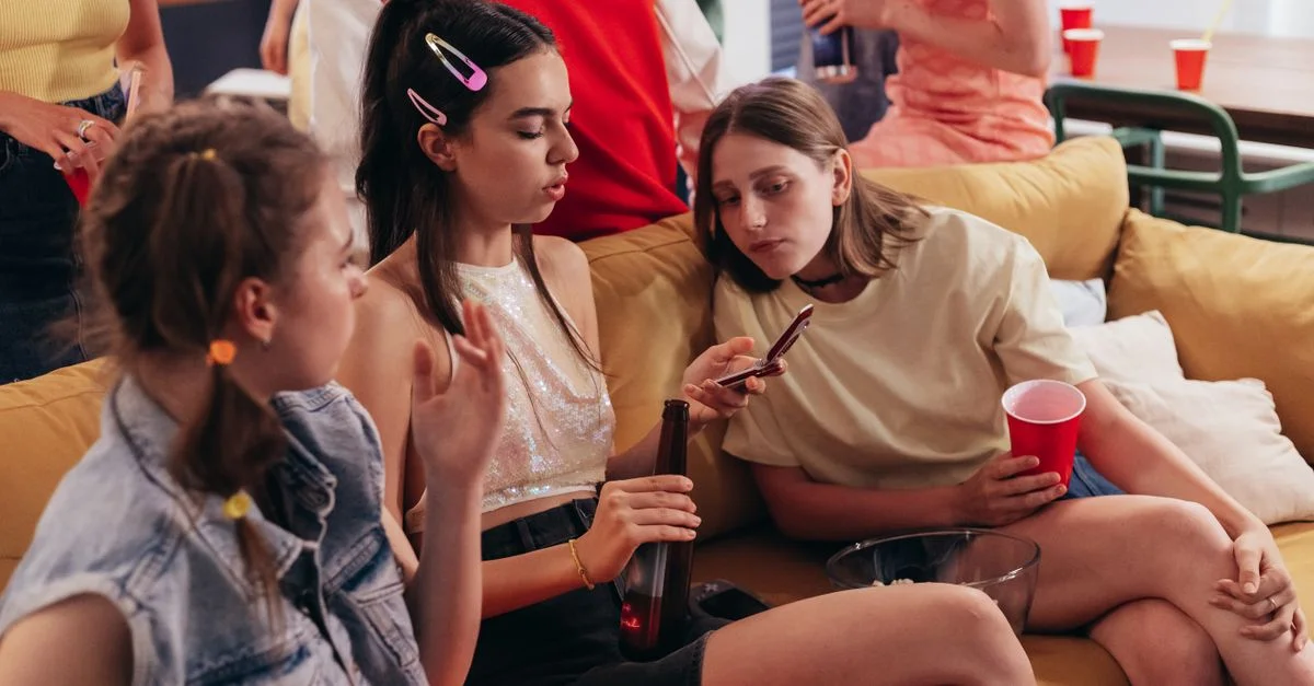 Jeunes femmes lors d'une fête décontractée à la maison, discutant et utilisant des téléphones portables.