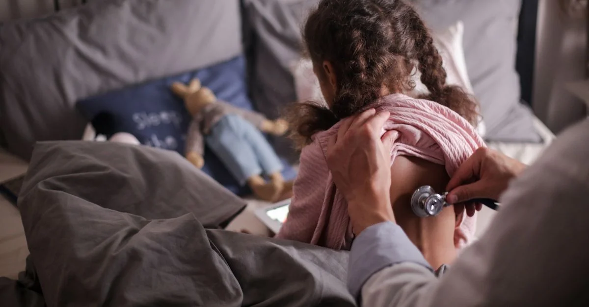 Un pédiatre vérifie le dos d'un enfant avec un stéthoscope dans une chambre confortable.