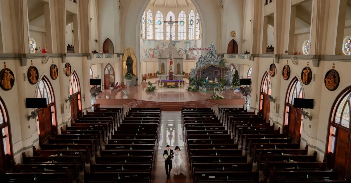 Le marié et la mariée marchent dans l'allée d'une grande église ornée pendant une cérémonie de mariage.