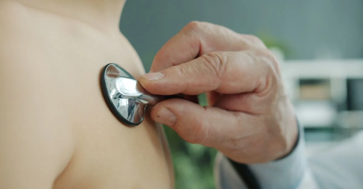 Gros plan sur un médecin utilisant un stéthoscope sur la poitrine d'un enfant, à l'intérieur.