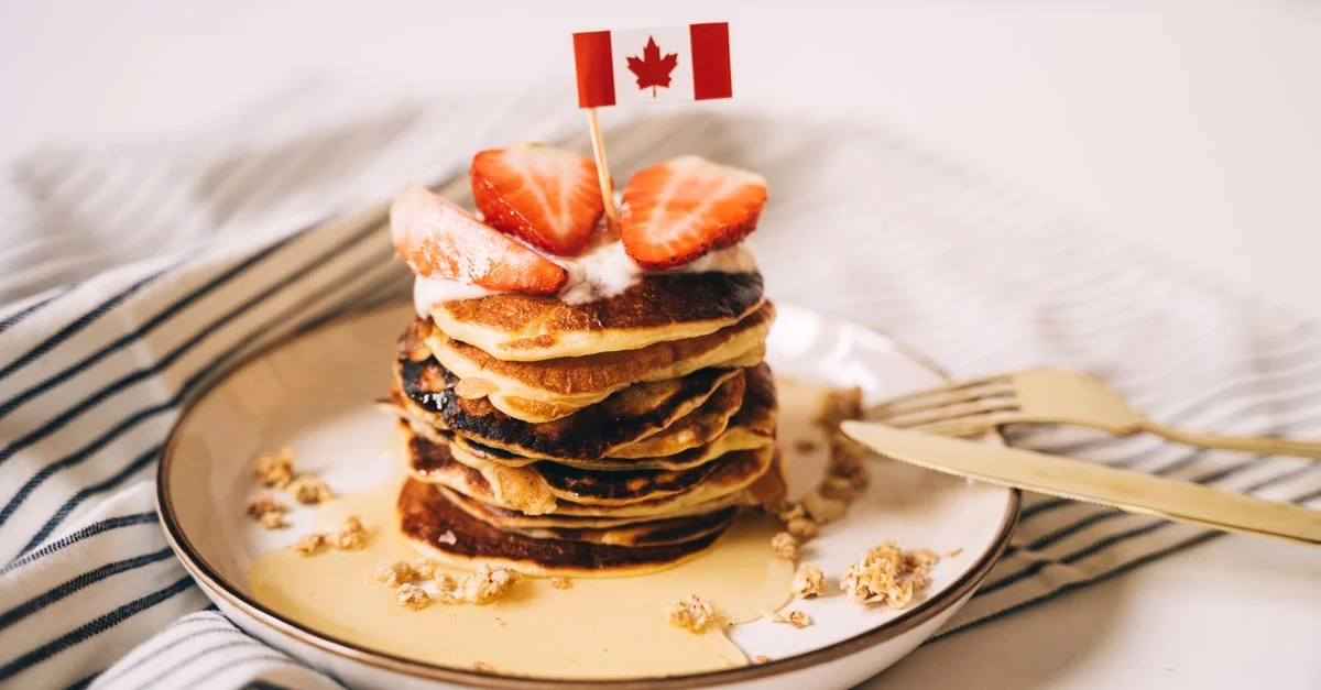 Délicieuses crêpes surmontées de fraises fraîches et de sirop d'érable, avec un drapeau canadien.